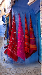 Colorful textiles hanging on a blue wall in the medina in Chefchaouen, Morocco