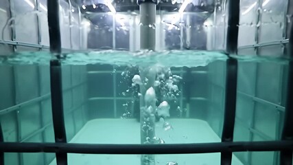 Water filled container viewed through bars, bubbles rising in blue-green liquid - Powered by Adobe