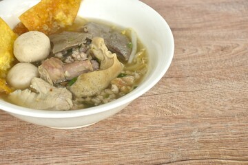 boiled pork ball and entrails with chop pork in clear soup on bowl topping fried crispy yellow dumpling paste