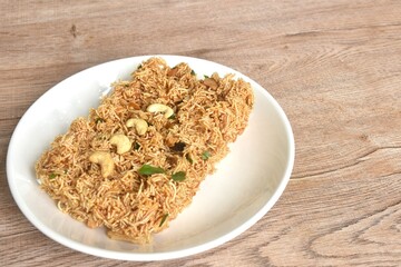 crispy fried thin rice noodles with coconut cream topping cashew nut and slice  seville orange on plate