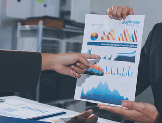 Focused young businessman signing agreement with skilled lawyer in eyeglasses. Concentrated financial advisor showing place for signature on paper contract document to male client at meeting in office