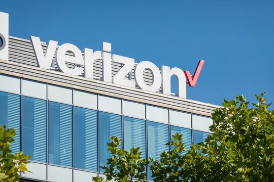 Banner of Verizon mobile carrier on modern building behind trees