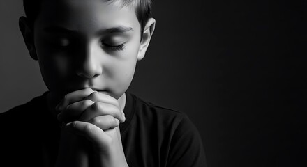 A thoughtful boy with clasped hands conveys a deep sense of prayer and reflection, perfectly capturing serenity and introspection in monochrome.