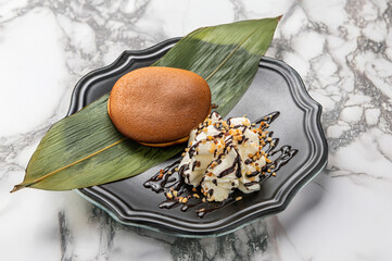 Japanese dorayaki with creamy vanilla gelato, chocolate drizzle, and hazelnut sprinkles on a sleek black plate, isolated on a marble background with veins.