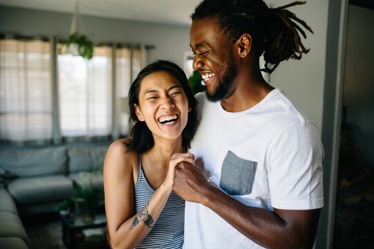 Happy diverse couple laughing together at home enjoying life and love relationship