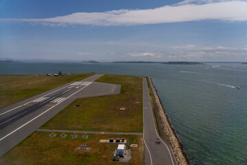 Aerial view of airport runway near ocean on sunny day.