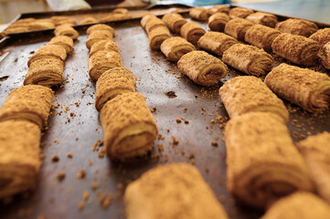 Rolled pastries filled with sweet filling arranged on a baking tray in a warm kitchen setting for a...
