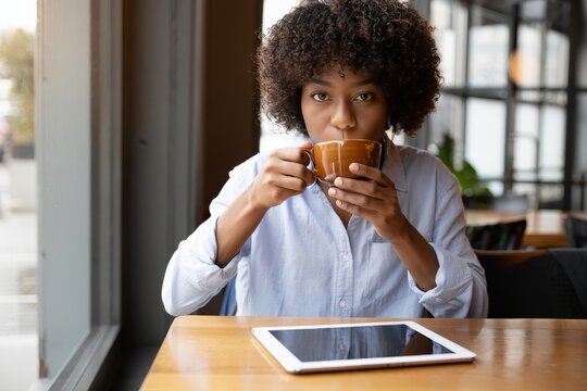 African american woman drinking coffee in cafe working on tablet business lifestyle - Powered by Adobe