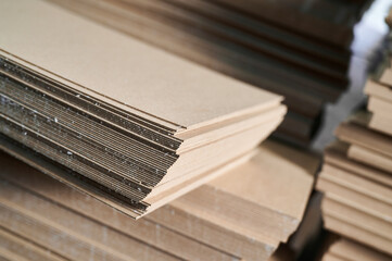 Stacks of thick paperboard prepared for the manufacturing process of sturdy cardboard boxes in an...