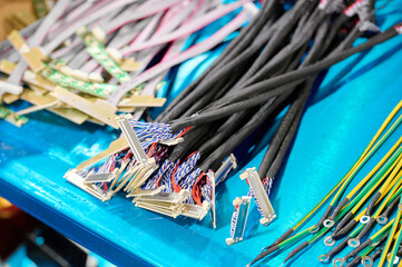 Various electronic wires and connectors displayed on a blue surface in a workshop during daylight