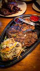 juicy grilled T bone steak, perfectly seared, served alongside a loaded baked mash potato on a...