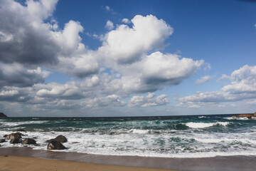 Tranquil Rocky Shoreline Under Blue Sky and Clouds