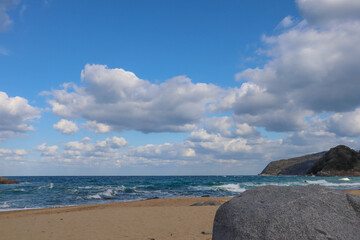 Tranquil Rocky Shoreline Under Blue Sky and Clouds