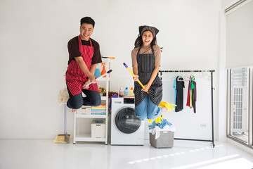 Asian young couple ride mop and broomstick while jumping in air