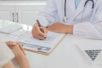 A uniformed doctor consults with a teenage patient in a hospital office, explaining the diagnosis,...