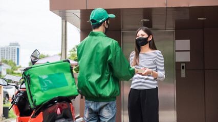 Asian deliveryman by motorbike give pizza in paper box to female customer