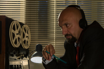 A special services officer records information on a tape recorder and listens in on the...