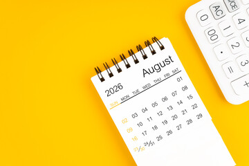 August 2026 calendar and calculator on yellow background, Flat lay.
