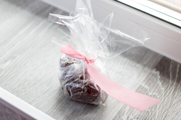 A clear plastic bag that has a pink ribbon gracefully wrapped around it