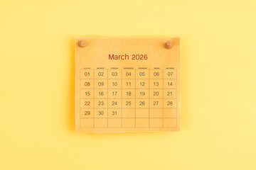 March 2026 brown calendar with wooden thumbtack on yellow color background.