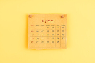 July 2026 brown calendar with wooden thumbtack on yellow color background.