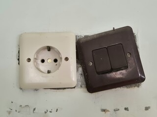 Wall mounted electrical socket and dual light switch with aged and dusty surface