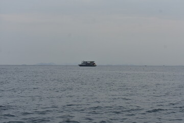 Small ferry boat on the calm ocean under an overcast sky.