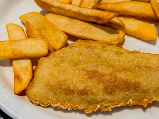Fried cod fish and chips on a white plate close up