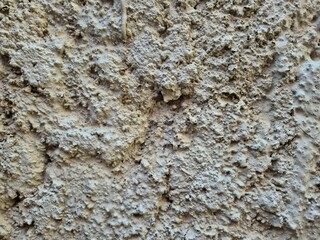 Close-up of rough textured concrete wall with uneven bumpy surface and weathered appearance