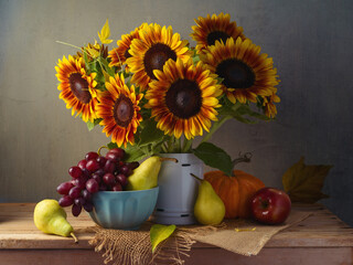 Autumn still life with sunflowers, grapes, pumpkin and pears on wooden table