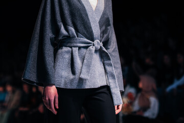 Autumnal women fashion, gray cardigan with belt on black background. 
