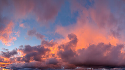 Fototapeta premium Dramatic sunrise with gradient orange and purple clouds, creating a panoramic abstract sky view.