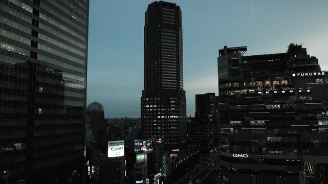 Night in Tokyo : Skyscraper Towering in front of an Urban Station at Dusk and the Lights of a Motorcade on the Elevated Highway Below  |  Shibuya, Tokyo, Japan