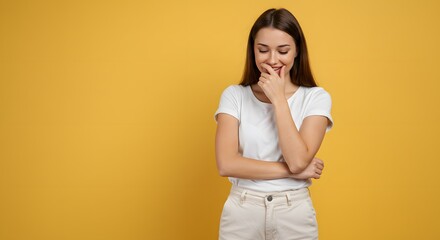 Joyful young woman giggling with hand covering mouth in a bright studio setting, radiating positive emotion and lightheartedness.