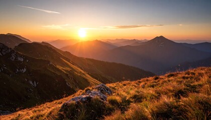 Golden sunrise over a mountain range. Lush, grassy hillsides slope gently down to the misty peaks below