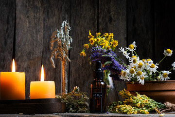 Herbal medicine. Medicinal herbs and candles on wooden background.