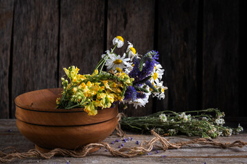 Wild herbs in wooden cup on wooden background. Traditional medicine.