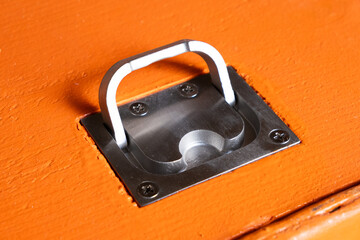 Closeup hidden metal handle on an orange wooden door.