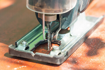A carpenter cuts a board with an electric jigsaw