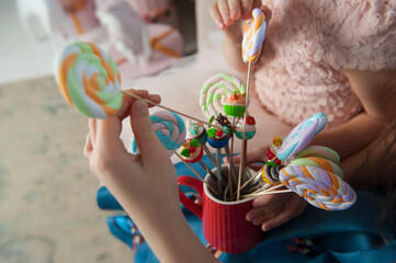 Children take colorful lollipops out of a glass