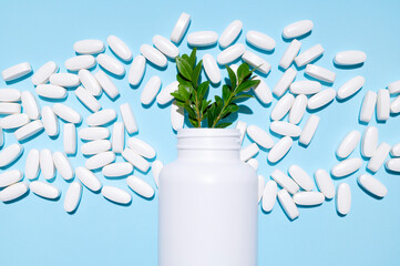 White container, plastic packaging and scattered white tablets, vitamins, pills, food supplements on blue background top view. Medical and pharmaceutical concept, health concept