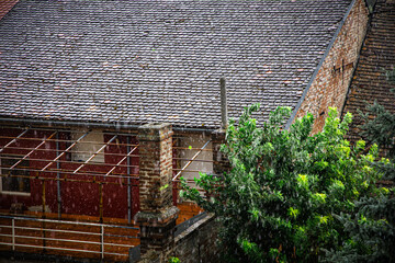 Downpour blurs view of tiled rooftops