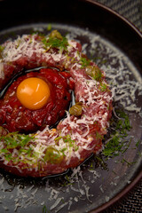 A Delectable Culinary Creation Featuring Fresh Ingredients, Raw Meat arranged in a Circle with Egg Yolk Centered Surrounded by Tomato Sauce Finely Grated Cheese and Herbs