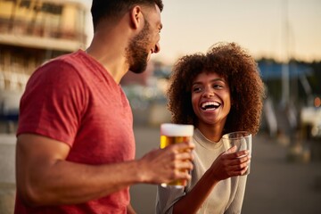 Couple enjoying beer at sunset outdoor happy hour drinks and good times together scene