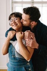 Happy couple embracing and kissing cheek at home, romantic relationship and love concept
