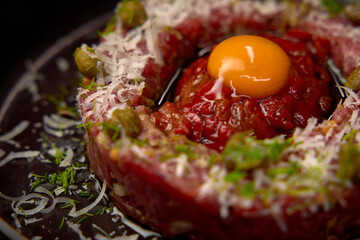 Deliciously Crafted Beef Tartare Surrounded by Fresh Ingredients and a Beautiful Egg Yolk at the...