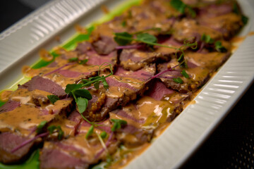 A Culinary Delight of Succulent Slices of Beef Tenderloin Served on a White Platter with Rich Sauce...