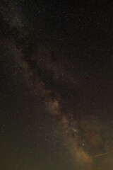 Against a dense field of stars and the glowing path of the Milky Way, a single streak cuts...