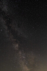 Against a dense field of stars and the glowing path of the Milky Way, a single streak cuts...