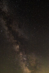 Against a dense field of stars and the glowing path of the Milky Way, a single streak cuts through—like a whispered wish flung across the dark canvas of eternity